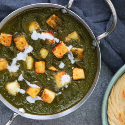 Stock photo showing elevated view of Palak paneer being served in a handled dish (Kadhai / Balti pan). This is an Indian vegetarian dish consisting of paneer, similar to cottage cheese, in pureed spinach flavoured with spices including ginger, garlic and garam masala.