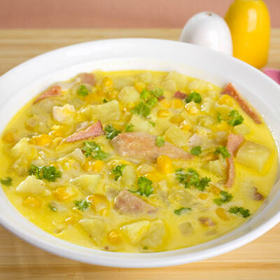 A bowl of corn chowder with bacon, potatoes and chicken.
